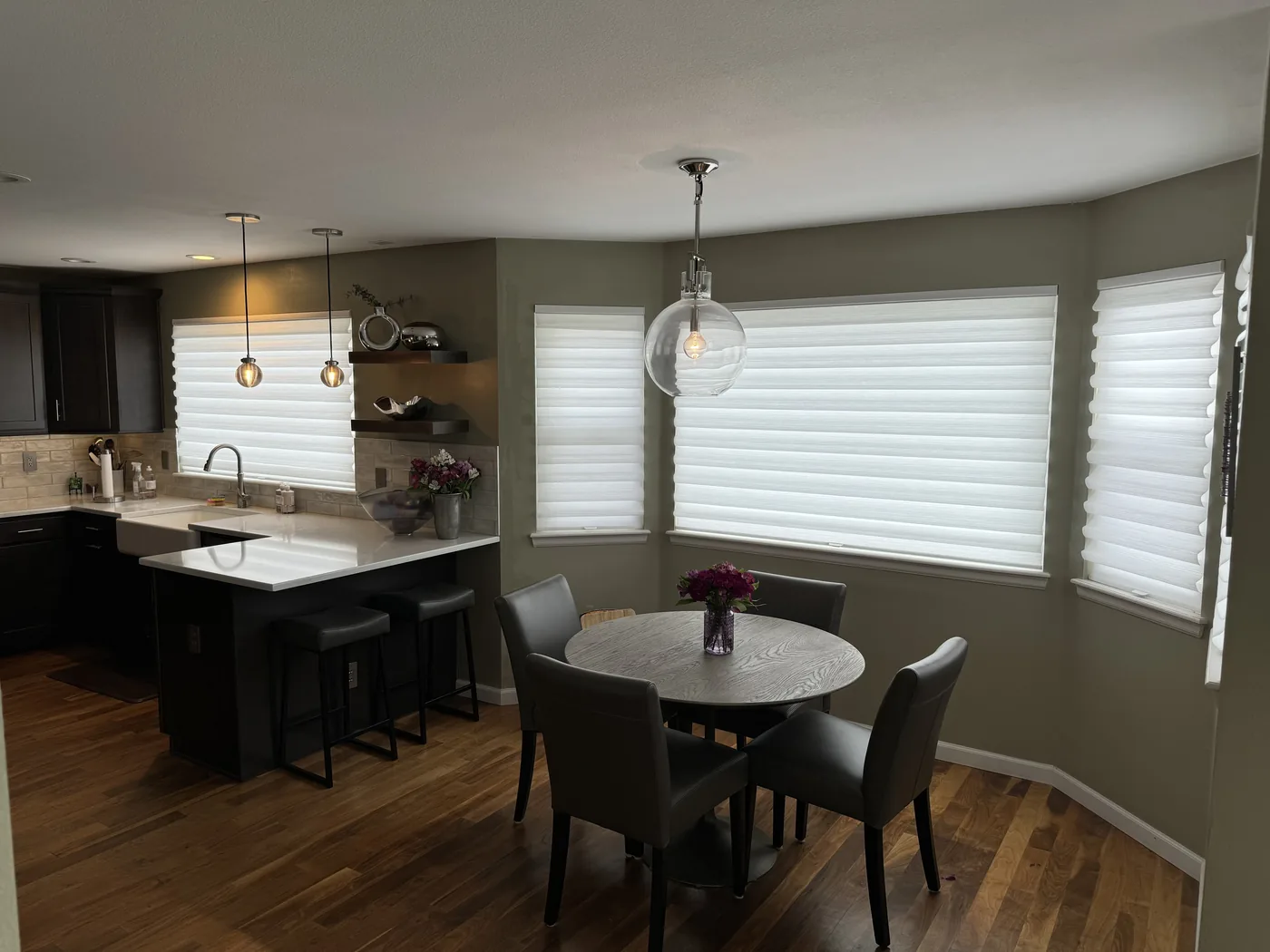 White Roman shades installed in a modern kitchen and dining room at dusk, Howard's Draperies, Boulder Colorado