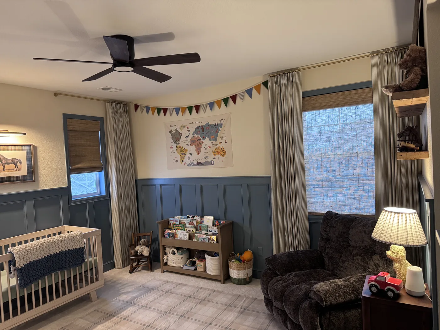 Woven wood shades and ticking-stripe drapery panels in a child's nursery, custom window treatments by Howard's Draperies