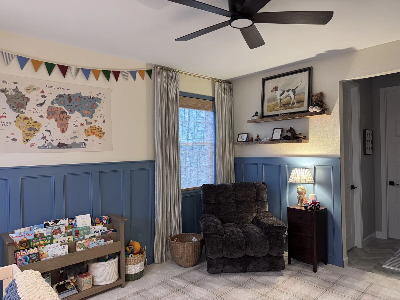 Ticking-stripe drapery panels layered with woven wood shades in a nursery corner window, Howard's Draperies Boulder